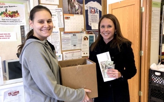 SouthPoint's branch president Megan Karg handing a box of food donations to the food shelf representative